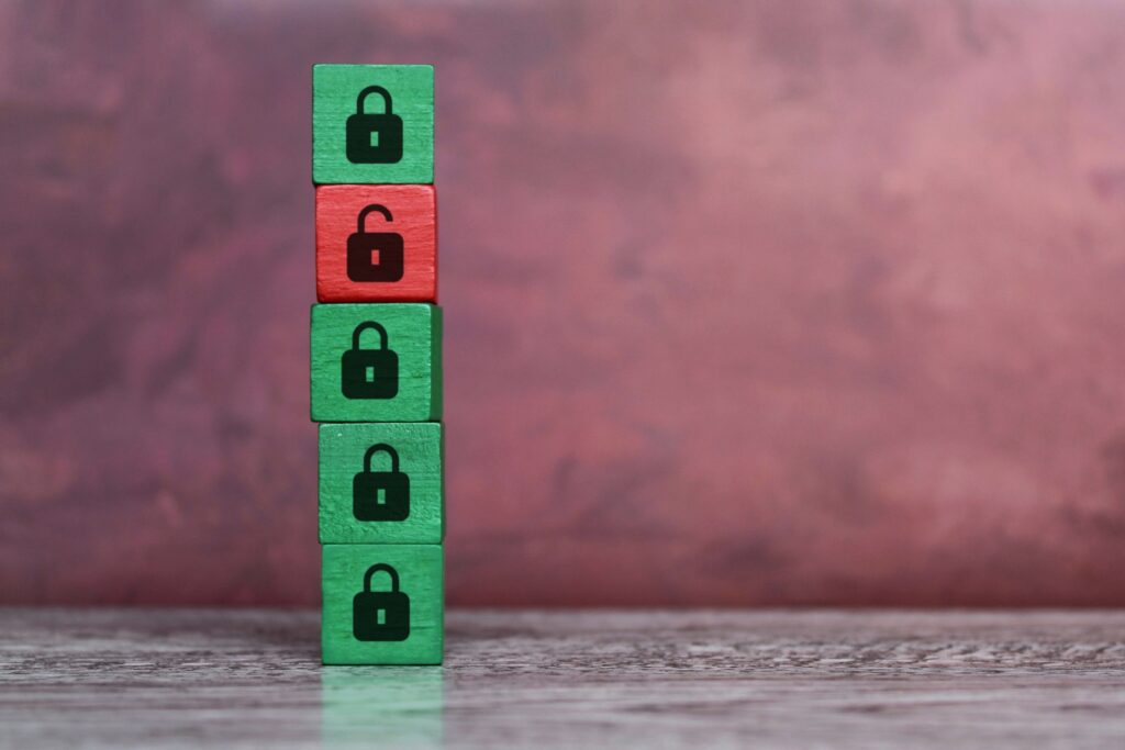 five wooden blocks in a tower. four of them are green with a locked padlock symbol and one of them is red with a unlocked padlock symbol