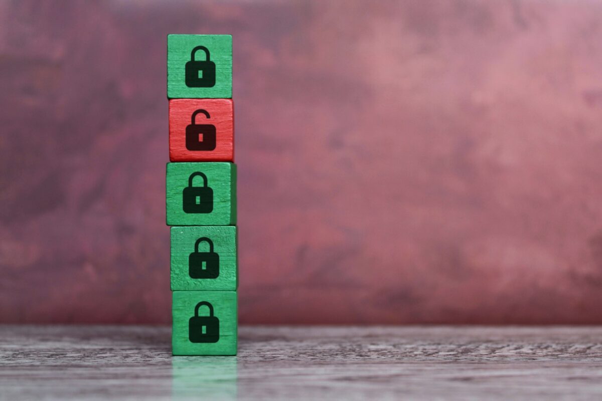 five wooden blocks in a tower. four of them are green with a locked padlock symbol and one of them is red with a unlocked padlock symbol